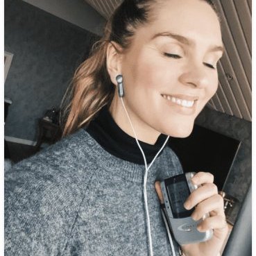 Woman relaxing with a handheld wellness device and earphones